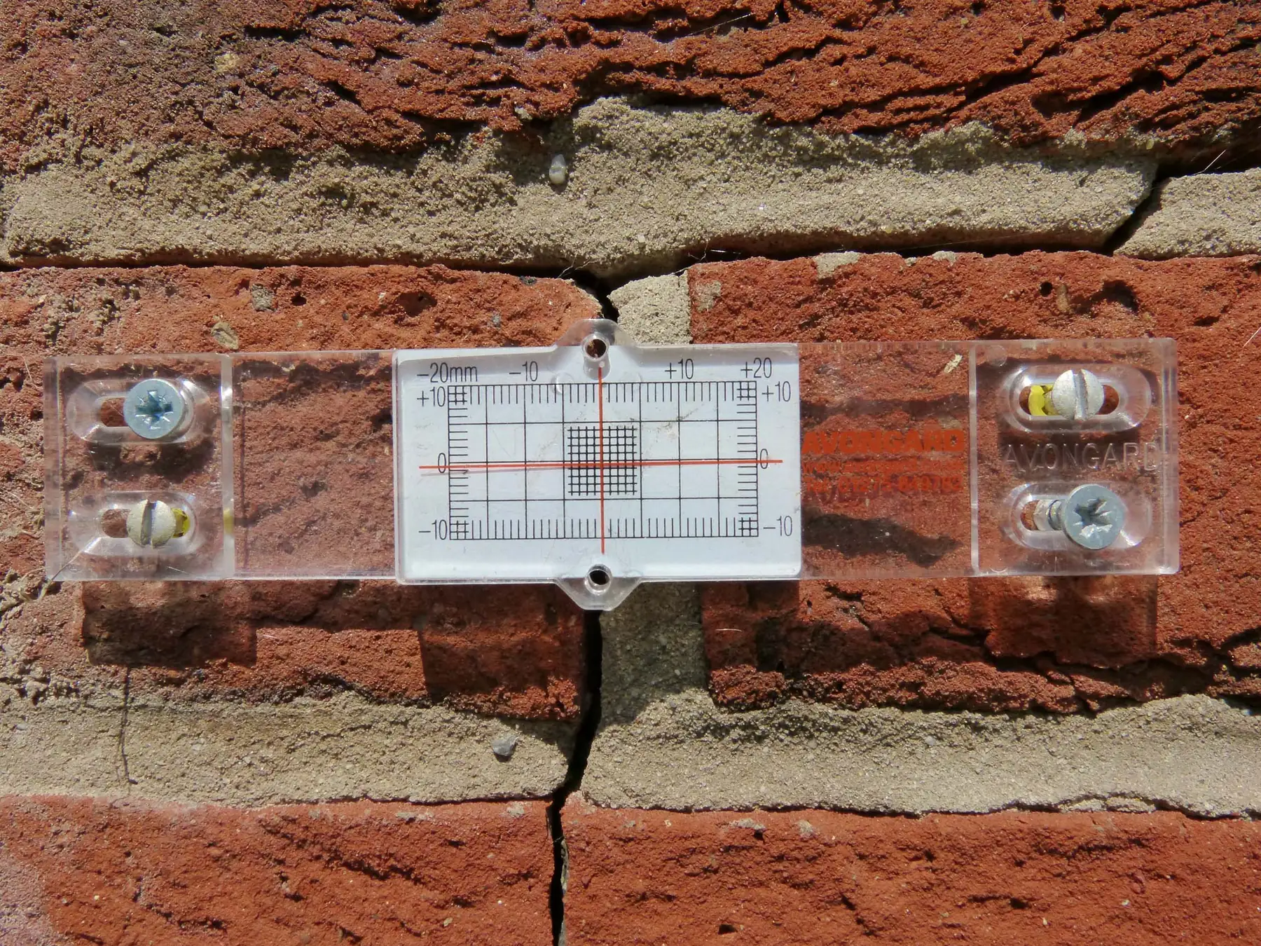 A crack-monitoring gauge fitted across a wall crack to measure structural movement